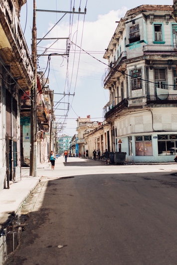 Havana street lined with weathered colonial buildings, crisscrossing power lines, and a few pedestrians