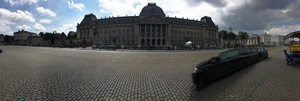 Panorama of a long ornate palace facade across a cobbled Brussels plaza, a black limousine parked in the foreground