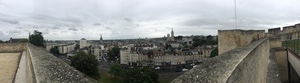 Panorama from stone ramparts over the rooftops and church spires of Caen under an overcast sky