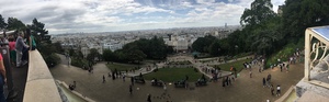 Panoramic view over Paris rooftops from the hilltop terrace at Montmartre, visitors lining the railing