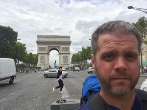 Selfie of a bearded man across the traffic circle from the Arc de Triomphe in Paris