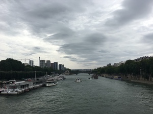 Boats and barges moored along the Seine in Paris under heavy grey clouds