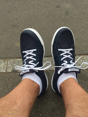 Looking down at navy sneakers with white laces and white socks on a Paris sidewalk