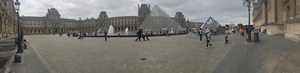 Panorama of the Louvre courtyard, visitors crossing the plaza around the glass pyramids