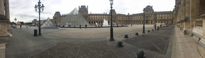 Panorama of the nearly empty Louvre courtyard with ornate lampposts and the glass pyramid at left