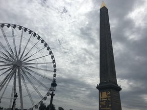 The Luxor obelisk and a large Ferris wheel at Place de la Concorde against dramatic grey clouds