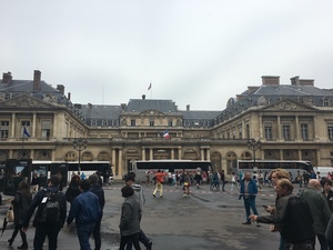 Crowds and tour buses outside the courtyard facade of the Palais Royal in Paris on an overcast day