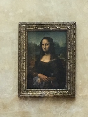 The Mona Lisa in its gilded frame on a plain wall at the Louvre