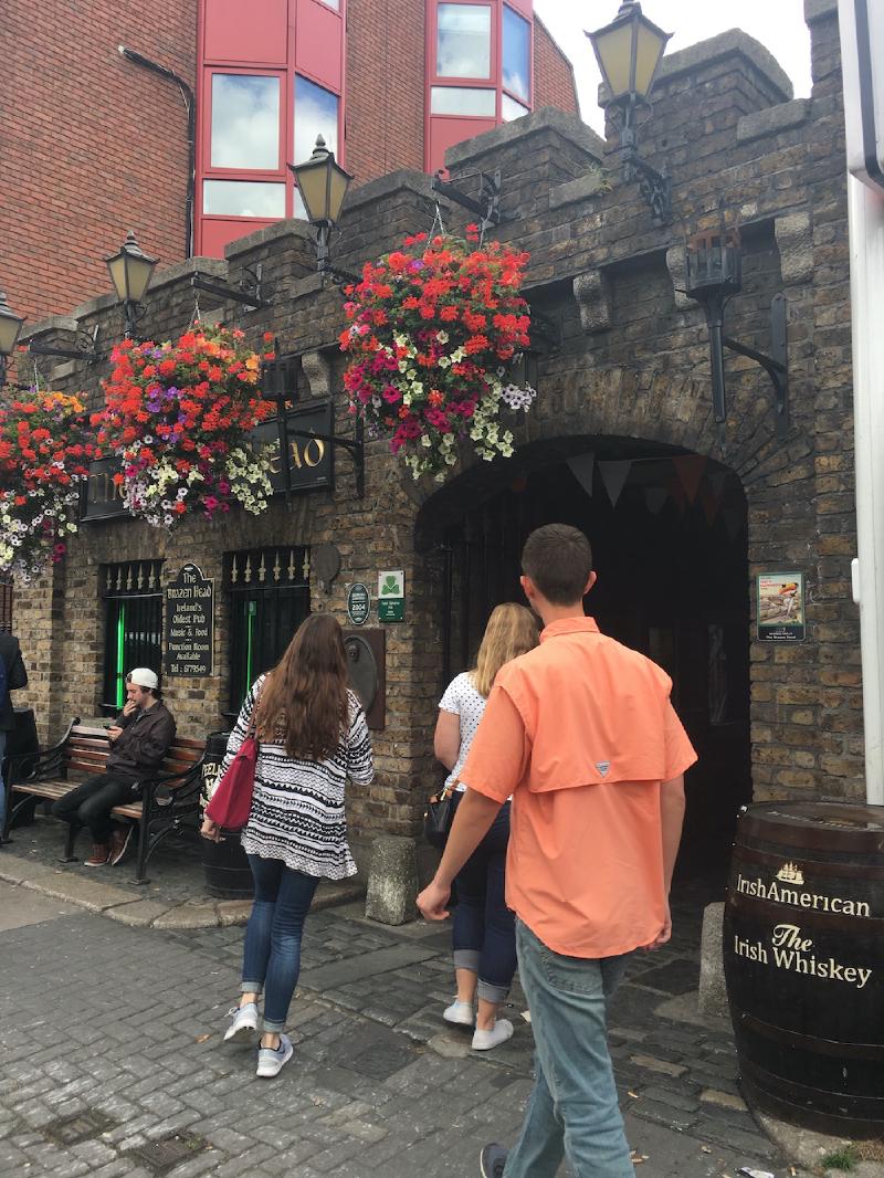 Visitors walk beneath hanging flower baskets into the stone entrance of the Brazen Head pub in Dublin