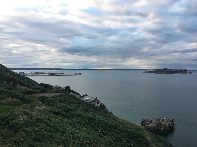 View from the Howth cliff path over the harbor, marina, and a small offshore island under an evening sky