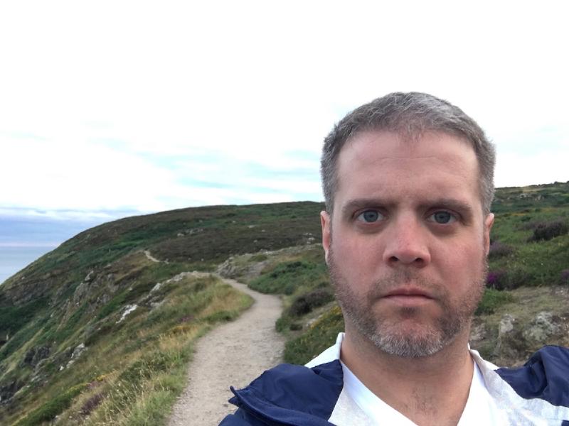Selfie on the Howth cliff walk, a dirt path winding along green headlands dotted with purple heather