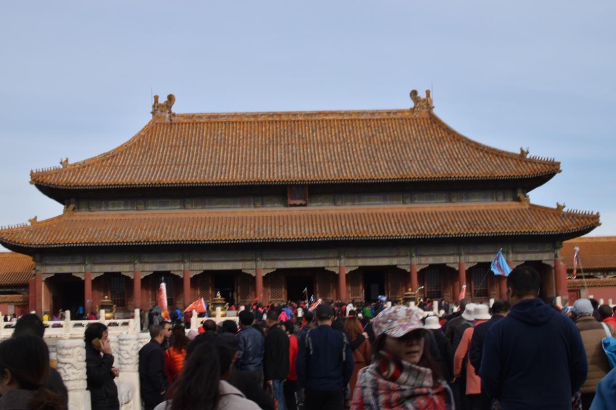 Crowds of visitors stream toward a golden-roofed palace hall in the Forbidden City