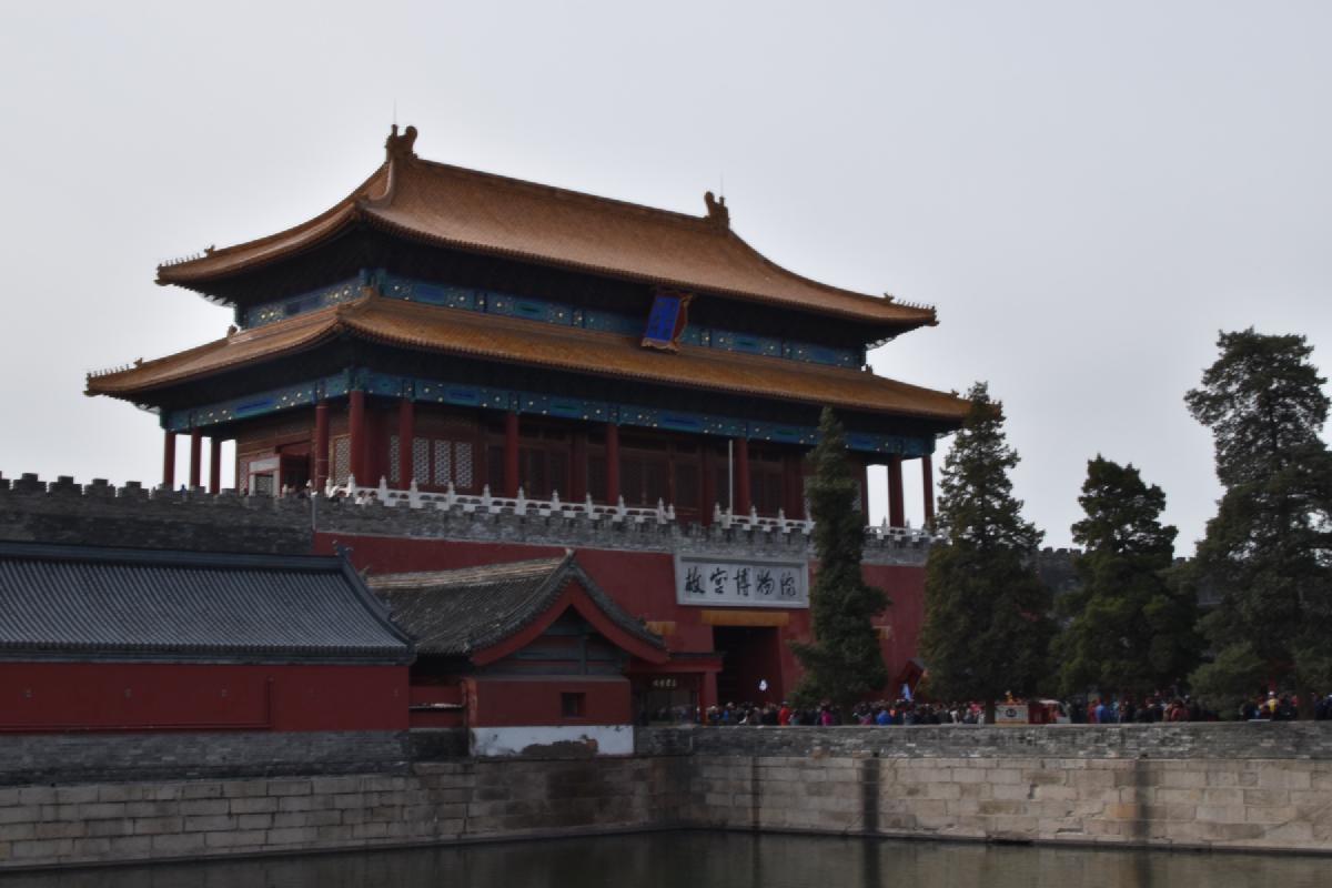 The Forbidden City&rsquo;s north gate tower with tiered golden roofs seen across its stone-walled moat
