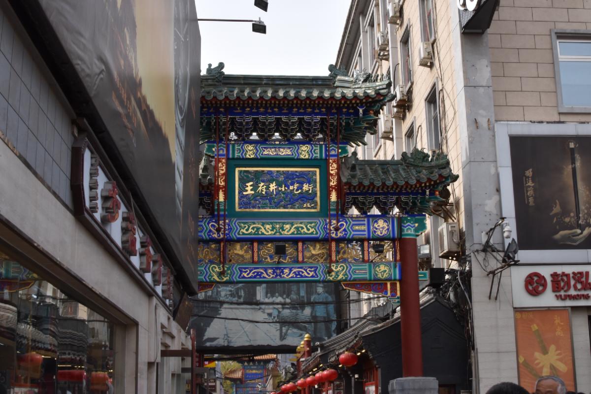 Ornate blue-and-gold archway with dragon panels spanning the entrance to Wangfujing snack street in Beijing