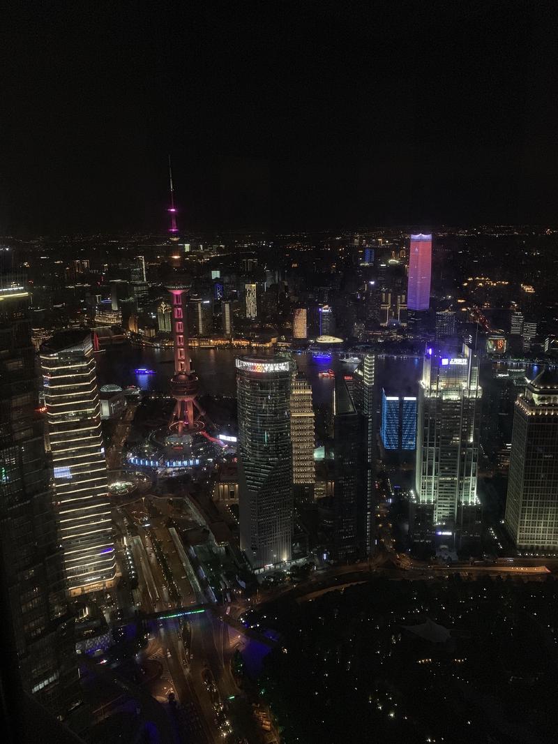 Shanghai at night from high above, the lit Oriental Pearl Tower among skyscrapers along the Huangpu River