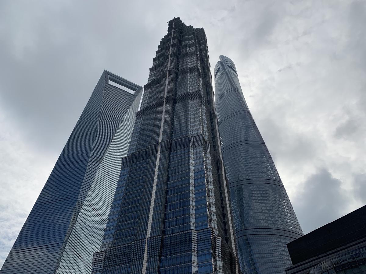 Three Shanghai skyscrapers seen from below against grey cloud: the World Financial Center, Jin Mao and Shanghai Tower