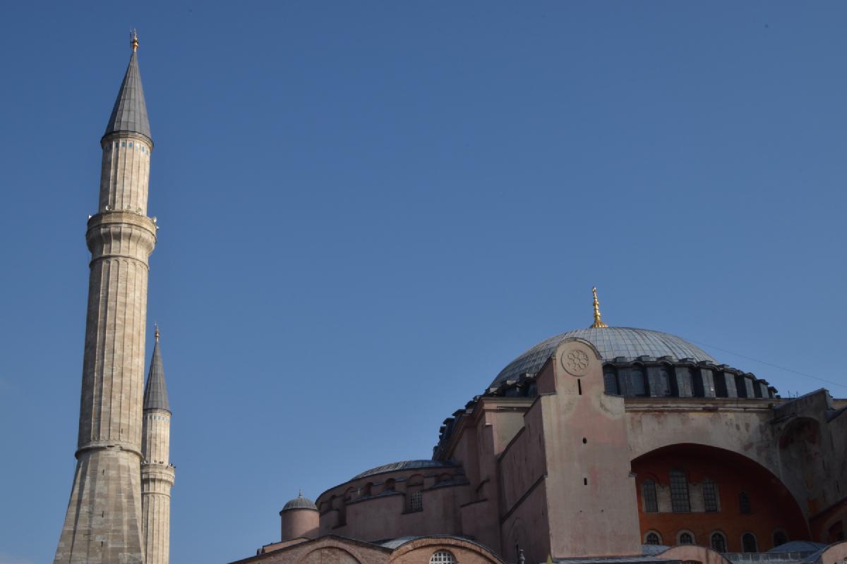 Two pointed minarets and the pink domed bulk of Hagia Sophia in Istanbul against a deep blue sky
