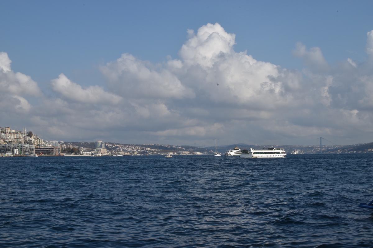 Ferries cross the choppy blue Bosphorus in Istanbul, hillside neighborhoods and a suspension bridge along the far shore