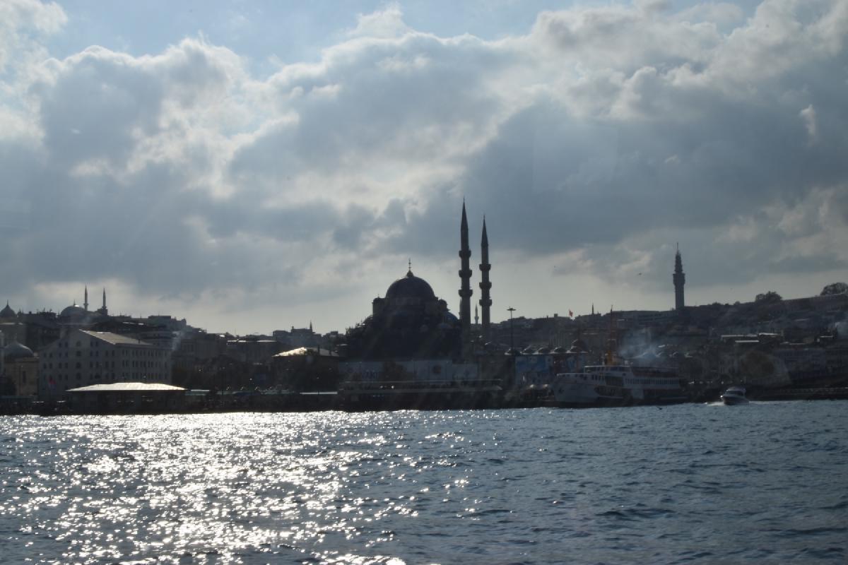 Istanbul skyline silhouetted from the water, mosque domes and minarets rising over ferries and sun-sparkled waves
